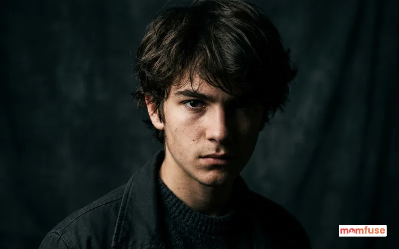 realistic portrait of a mysterious man, half face in shadow, serious expression, studio lighting.