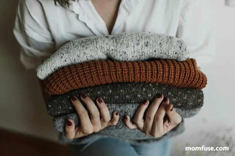 Person holding stack of knitted fabrics.