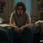 A stressed college student sitting on their bed with a frustrated expression.