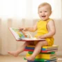 toddler sitting on a stack of colorful books.