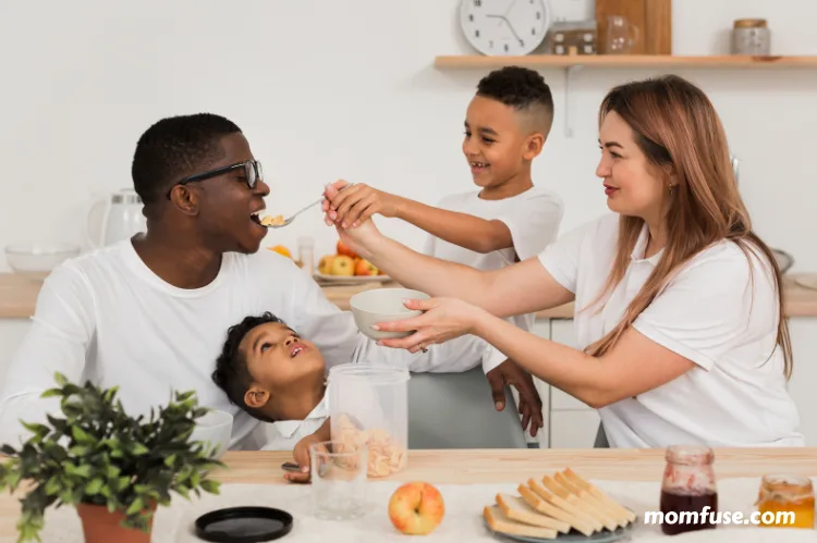 Mom and son feeding father some food.