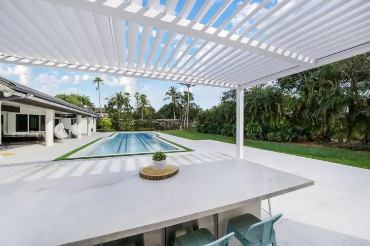 A couple in their backyard choosing between a sleek motorized pergola and a stylish manual pergola.