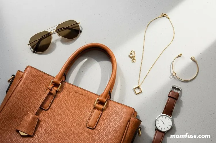A fashion flat-lay featuring timeless accessories: a leather handbag, minimalist jewelry, wristwatch, and sunglasses.