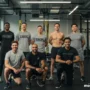 A diverse group of gym trainers in a modern fitness studio, smiling confidently.