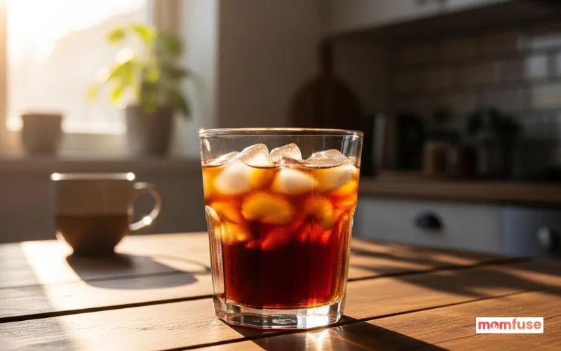 cold brew coffee in a glass with ice cubes, wooden table, morning sunlight, cozy home kitchen background.