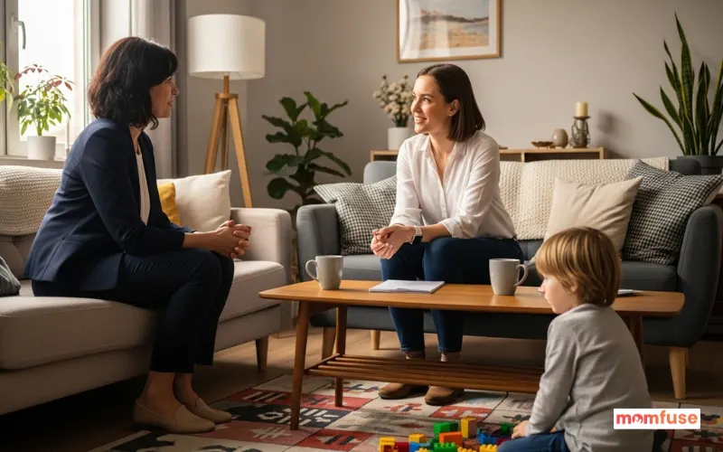 Parent interviewing nanny in living room while child plays nearby, friendly conversation.