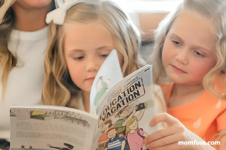 Two child girls reading a book.