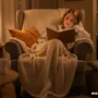 A cozy living room setting with a tired mother in a soft blanket reading a book.
