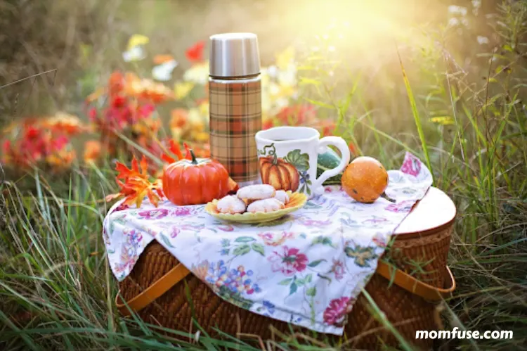 Autumn picnic setup on a wicker basket with a floral cloth.