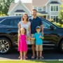 Happy family standing beside a sleek preowned SUV in a suburban driveway, bright sunny day.