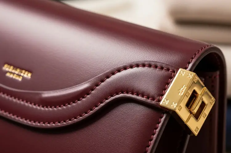 a high-end handbag’s stitching, gold hardware, and fine leather texture, symbolizing durability.