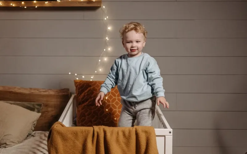 Toddler standing in a crib, perfect for rare but instantly wearable boy names inspiration.