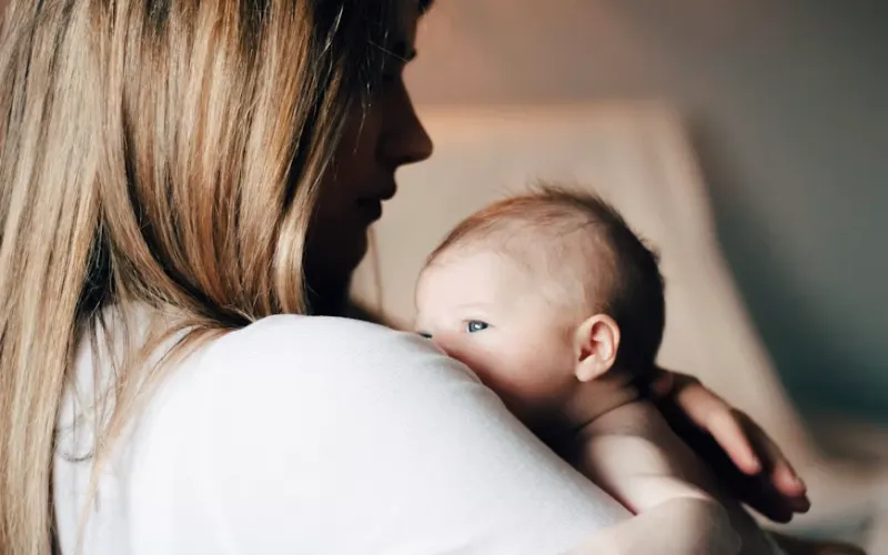 Mother holding her baby in a warm, close embrace.