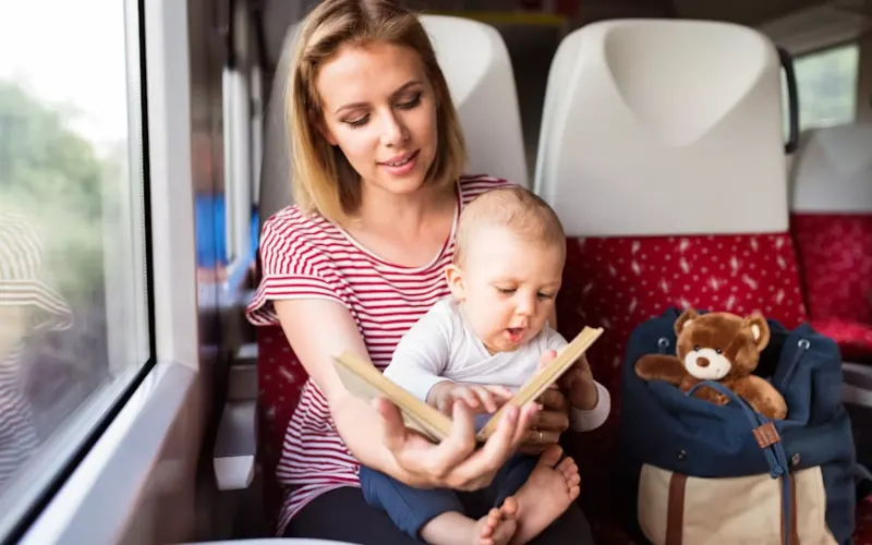 Mother reading a book with her baby while traveling on a train.