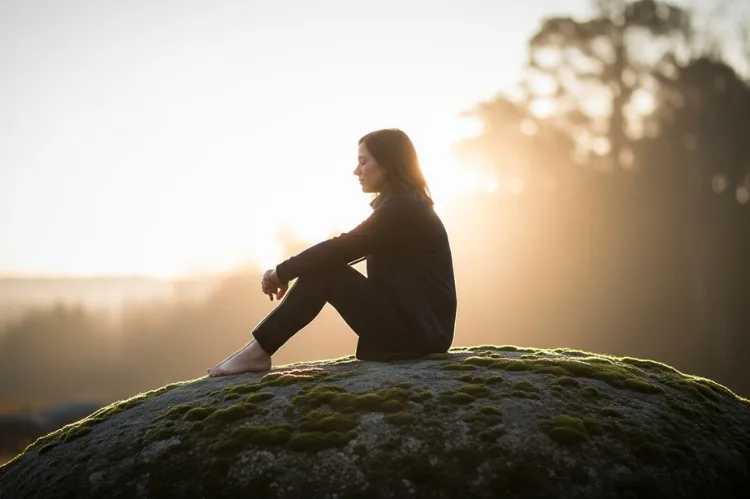 Person sitting calmly with a soft light around them.