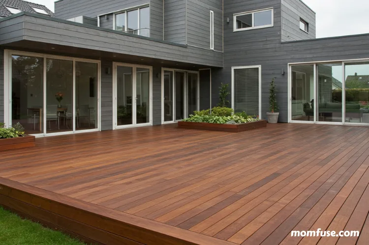 Elegant wooden deck with polished finish and decorative plants, connected to a stylish modern house.