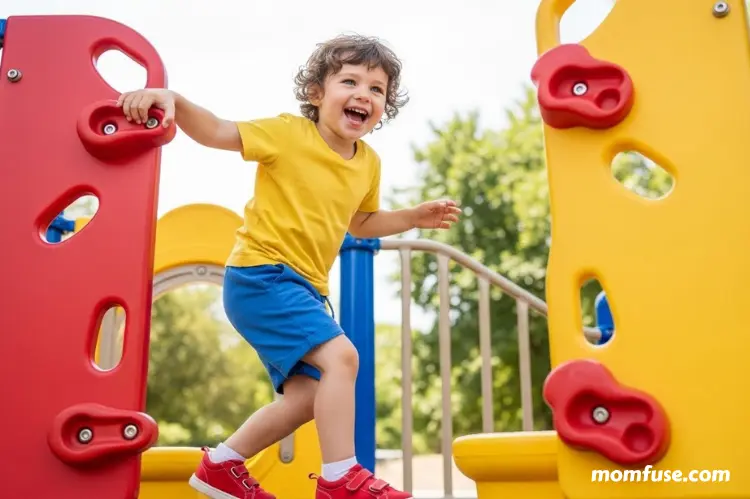 A young child climbing playground equipment outdoors, bright natural daylight, joyful expression.