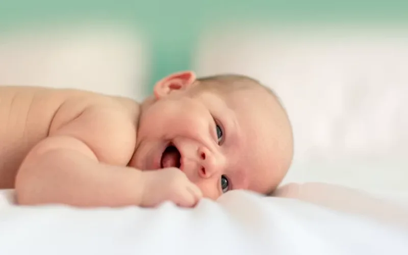 Smiling baby lying on a soft white blanket, representing unique baby boy names with meaningful inspiration.