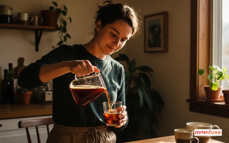 woman pouring cold brew into glass in morning sunlight, calm routine, cozy home vibe.