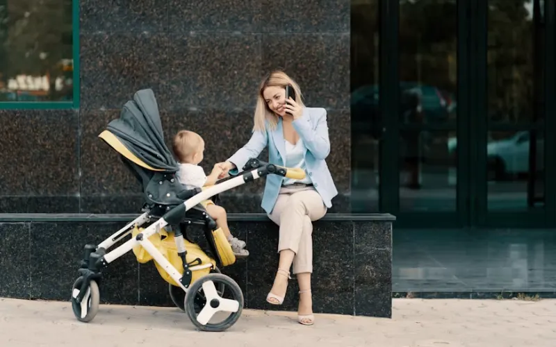Woman sitting beside a stroller with a baby in an urban setting.