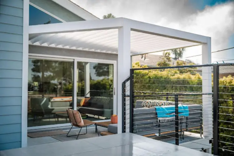Beautiful outdoor living space with a sleek aluminum pergola, adjustable louvers partially open.