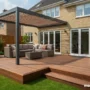 Beautiful modern wooden deck attached to a suburban home, surrounded by greenery and sunlight.